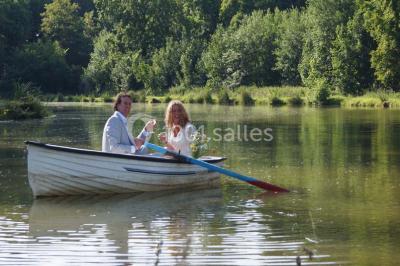 Une femme en robe de mariée défile sur un tapis rouge devant un public dans une salle éclairée par des lustres.