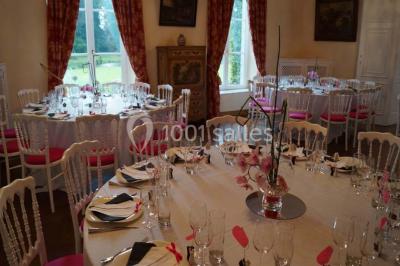 Une femme en robe de mariée défile sur un tapis rouge devant un public dans une salle éclairée par des lustres.