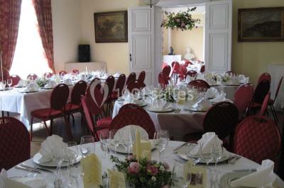 Une femme en robe de mariée défile sur un tapis rouge devant un public dans une salle éclairée par des lustres.