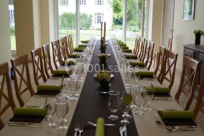 Une femme en robe de mariée défile sur un tapis rouge devant un public dans une salle éclairée par des lustres.