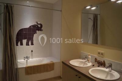 Une femme en robe de mariée défile sur un tapis rouge devant un public dans une salle éclairée par des lustres.