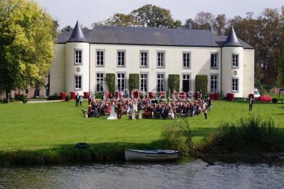 Salle de réunion avec une grande table en bois, chaises noires, bouteilles d'eau et vue sur l'extérieur par des baies…