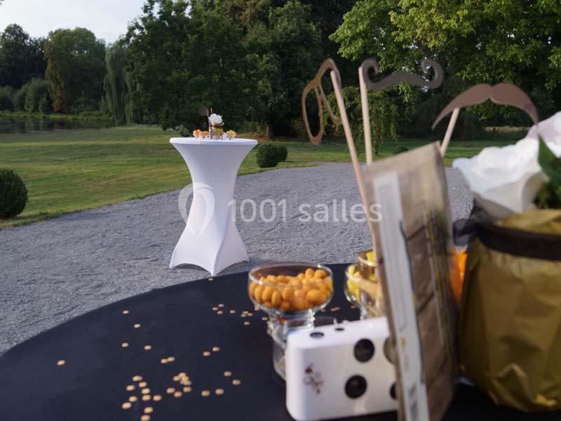 Table décorée avec des accessoires festifs et des amuse-bouches en extérieur, avec une table haute en arrière-plan.