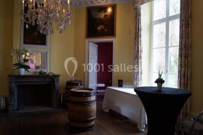 Salle de réunion avec une grande table en bois, chaises noires, bouteilles d'eau et vue sur l'extérieur par des baies…
