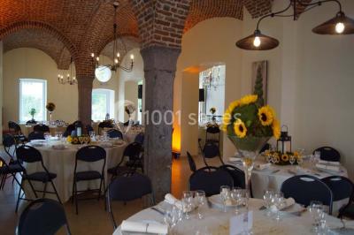 Salle de réunion avec une grande table en bois, chaises noires, bouteilles d'eau et vue sur l'extérieur par des baies…