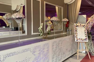 Salle de réception décorée avec des lumières roses et un éclairage scintillant, tables dressées et plafond drapé.