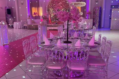Salle de réception décorée avec des lumières roses et un éclairage scintillant, tables dressées et plafond drapé.