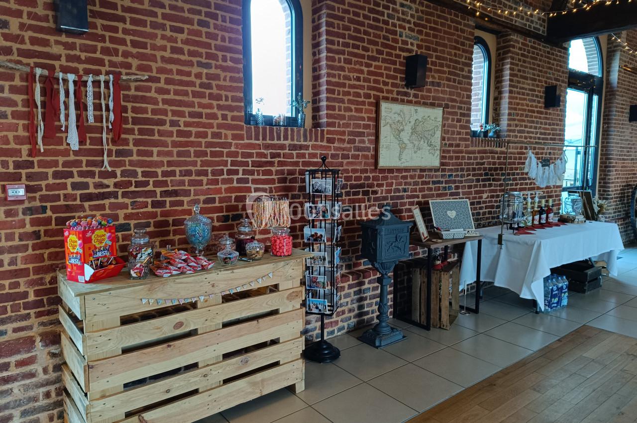 Stand de confiseries et décorations dans une salle en briques rouges avec des tables et des présentoirs.