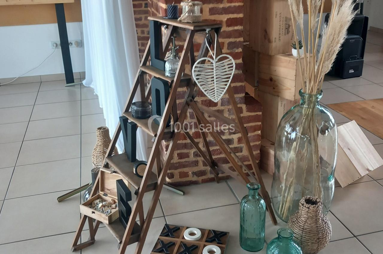 Échelle en bois décorative avec objets en osier, bougies et vases, posée près d'un mur en briques.