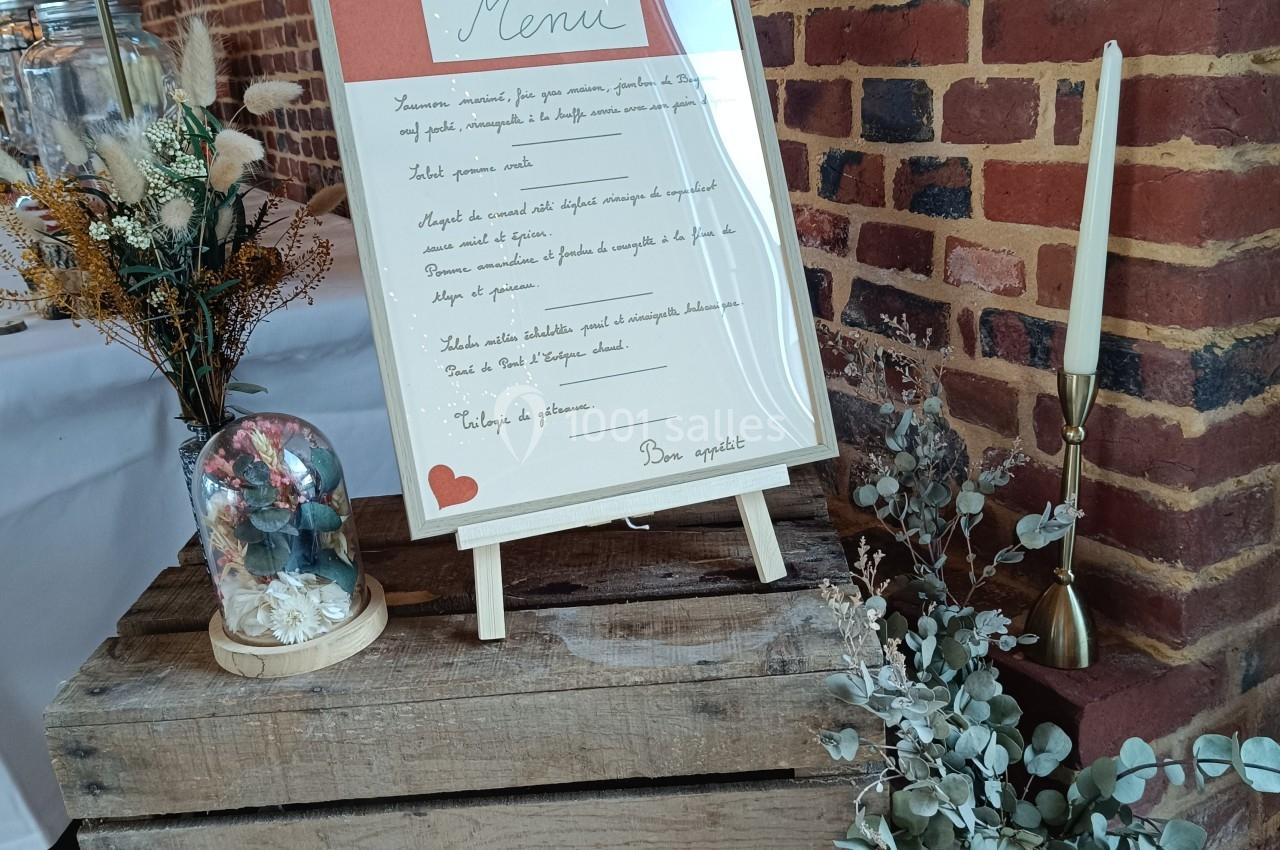 Ardoise de menu manuscrite posée sur une caisse en bois, entourée de décorations florales et d'objets décoratifs.