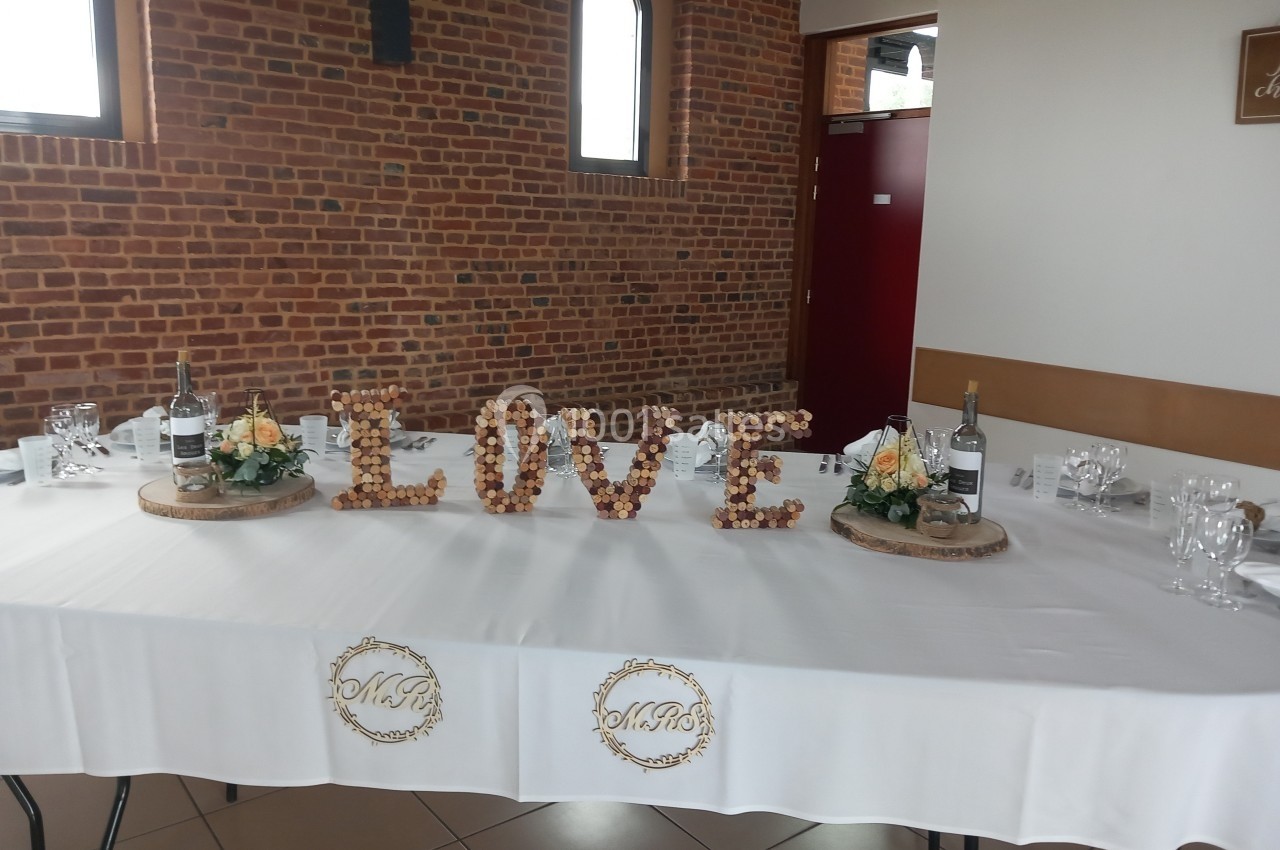 Table décorée pour un événement, ornée du mot ’LOVE’ en bouchons de liège, avec fleurs et bouteilles de vin.