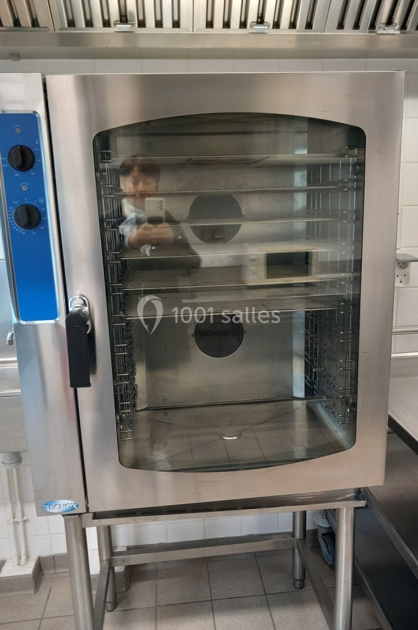 Four professionnel en acier inoxydable avec porte vitrée, installé dans une cuisine équipée de carrelage et d'inox.