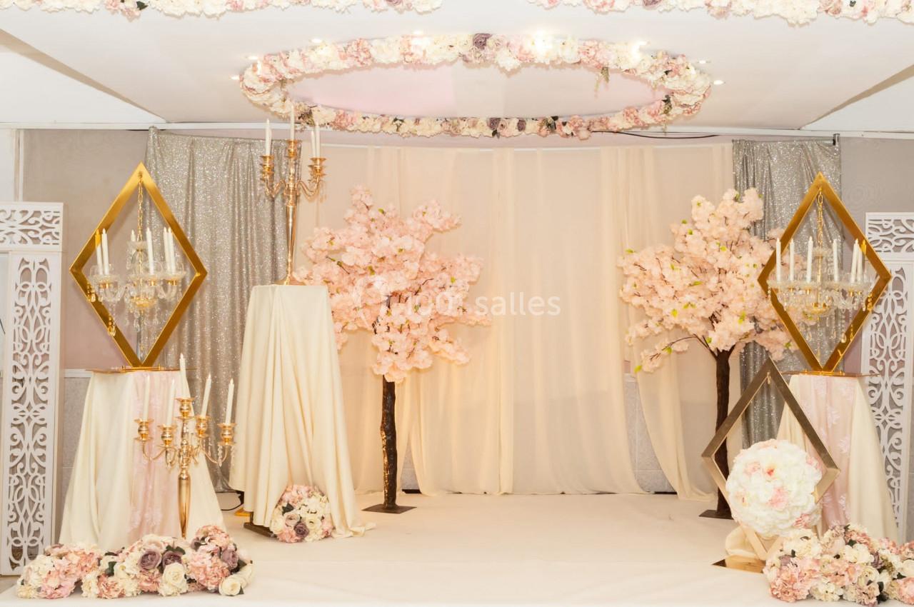 Location salle Brétigny-sur-Orge (Essonne) - La Joya Réception #21 Décoration de salle avec fleurs roses, chandeliers dorés et rideaux scintillants dans un cadre élégant et lumineux.