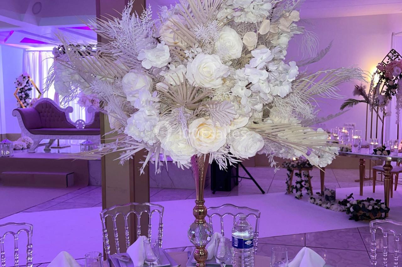 Location salle Brétigny-sur-Orge (Essonne) - La Joya Réception #18 Centre de table élégant avec des fleurs blanches et des feuillages, sur une table dressée dans une salle de réception.