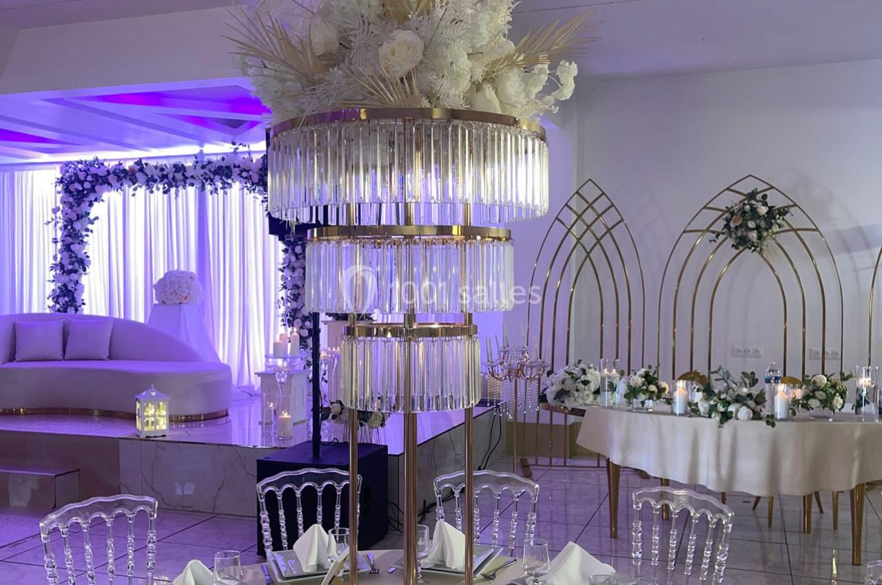 Location salle Brétigny-sur-Orge (Essonne) - La Joya Réception #17 Centre de table élégant avec pampas et fleurs blanches, entouré de décorations lumineuses dans une salle de réception.