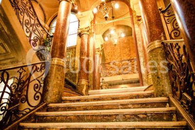 Miniature Location salle Paris 10 (Paris) - Delaville #13 Escalier en marbre avec rampes en fer forgé, colonnes décoratives et lustres suspendus dans un intérieur ancien.