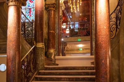 Miniature Location salle Paris 10 (Paris) - Delaville #6 Escalier en marbre avec rampes en fer forgé, colonnes décoratives et lustres suspendus dans un intérieur ancien.