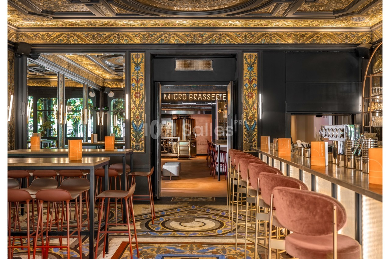 Intérieur d'une brasserie élégante avec un bar, des tabourets rembourrés et une décoration richement ornée.