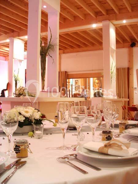 Table dressée avec vaisselle élégante, fleurs et décorations dans une salle lumineuse au plafond en bois.
