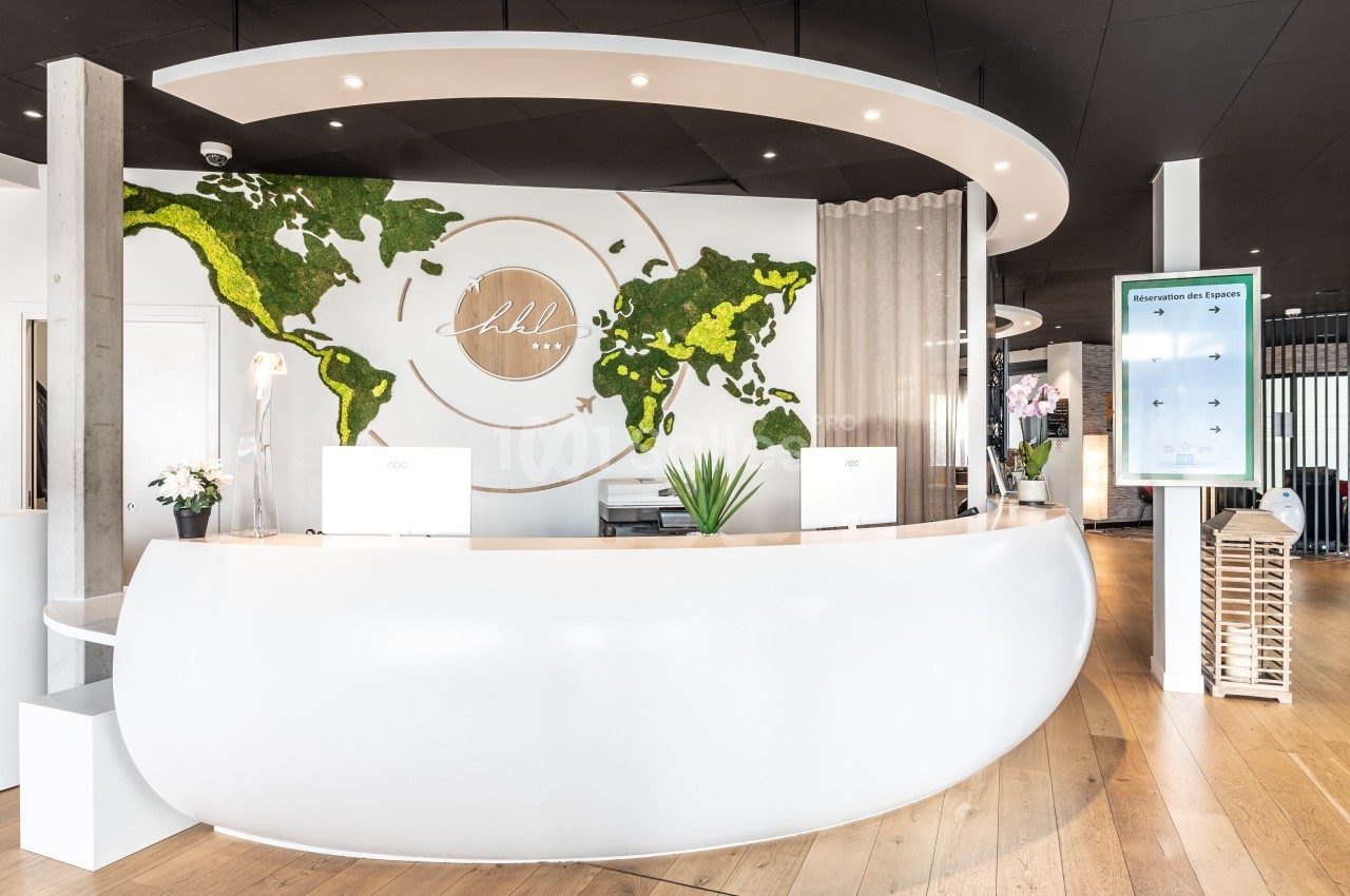Comptoir d'accueil moderne avec décoration murale représentant une carte du monde en mousse végétale.