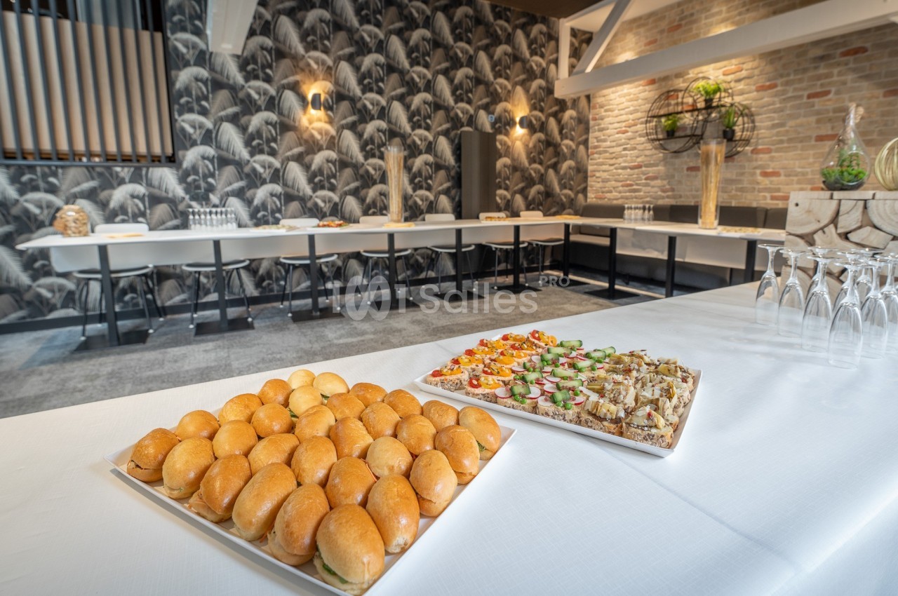 Plateaux de mini-sandwichs et amuse-bouches disposés sur une table dans une salle de réception élégante.