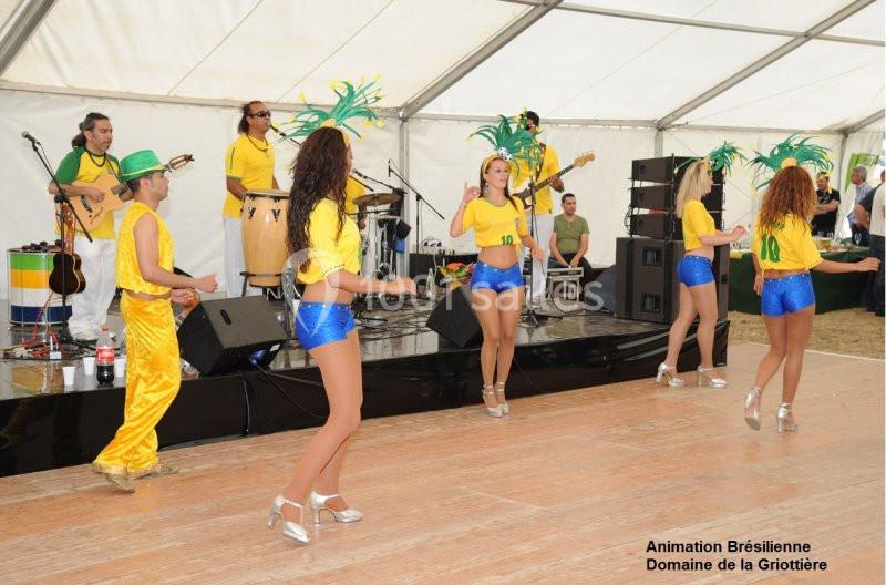 Danseurs et musiciens en tenue brésilienne se produisant sous un chapiteau lors d'un événement festif.