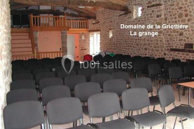Un groupe de personnes posant debout dans une pièce avec des murs en pierre et une table en arrière-plan.