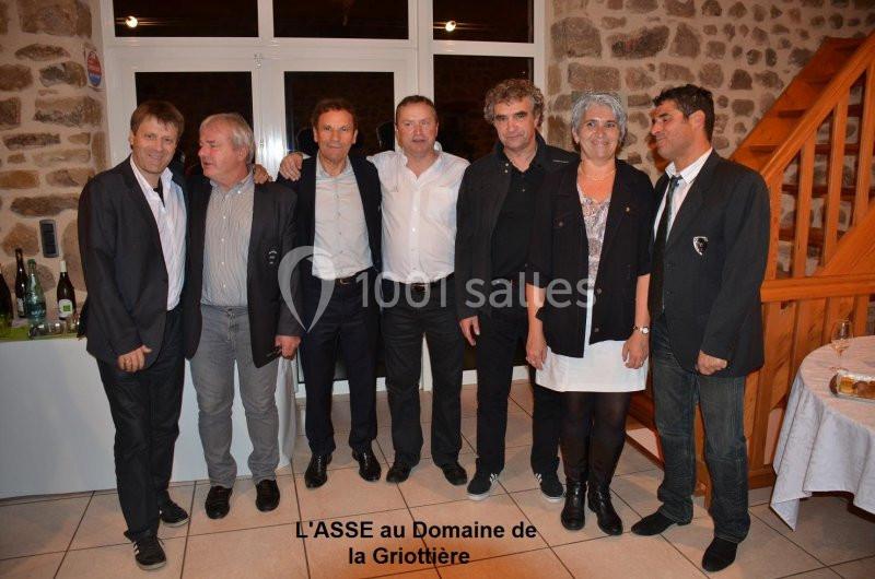Un groupe de personnes posant debout dans une pièce avec des murs en pierre et une table en arrière-plan.