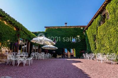 Décoration florale composée de roses, pivoines et feuillage, accrochée à une structure blanche en extérieur.