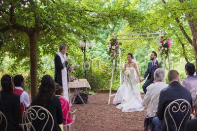 Décoration florale composée de roses, pivoines et feuillage, accrochée à une structure blanche en extérieur.