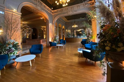 Hall spacieux avec sol en mosaïque, arches illuminées et tables décorées, éclairage chaleureux et ambiance élégante.