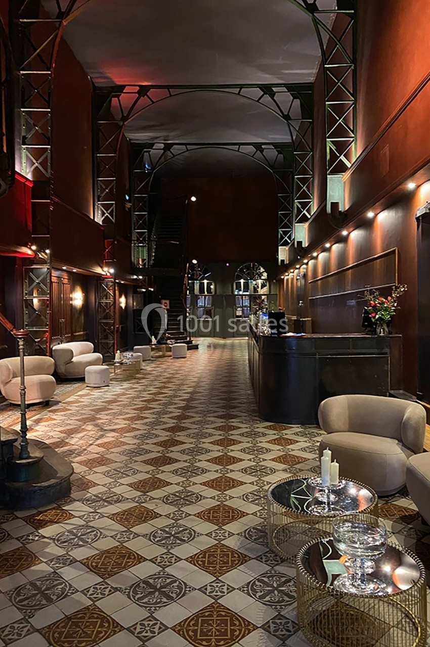 Hall d'entrée spacieux avec sol carrelé, mobilier moderne, comptoir d'accueil et éclairage tamisé.