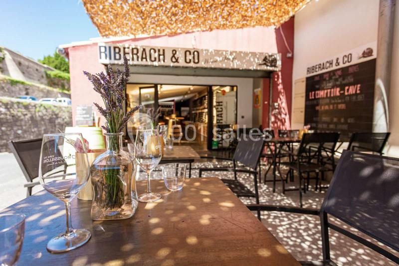 Terrasse ensoleillée d'un restaurant avec des tables dressées, des chaises et un bouquet de lavande au premier plan.