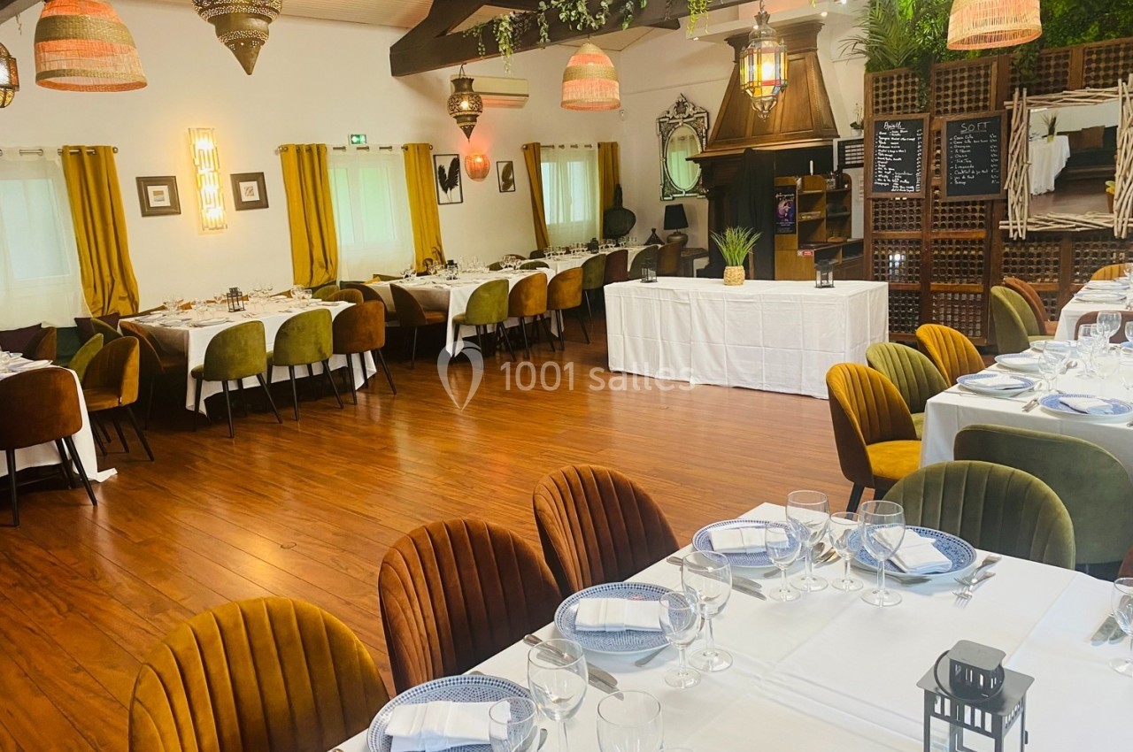 Salle de restaurant décorée avec des tables dressées, des chaises colorées et des luminaires suspendus.