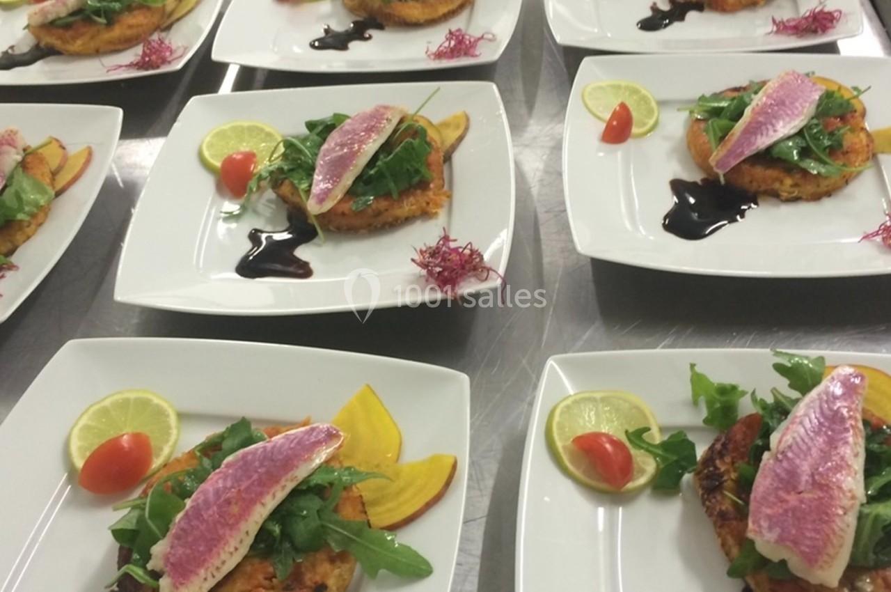 Assiettes dressées avec filets de poisson, galettes de légumes, roquette, tomates cerises et sauce balsamique.