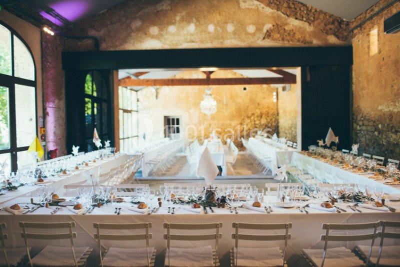 Location salle Piolenc (Vaucluse) - Château Beauchêne #10 Salle de réception avec de longues tables dressées pour un banquet, décorée dans un style rustique et lumineux.