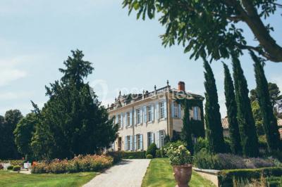 Miniature Location salle Piolenc (Vaucluse) - Château Beauchêne #3 Un couple en tenue de mariage sourit sur les marches d'un escalier en pierre devant une maison entourée de végétation.
