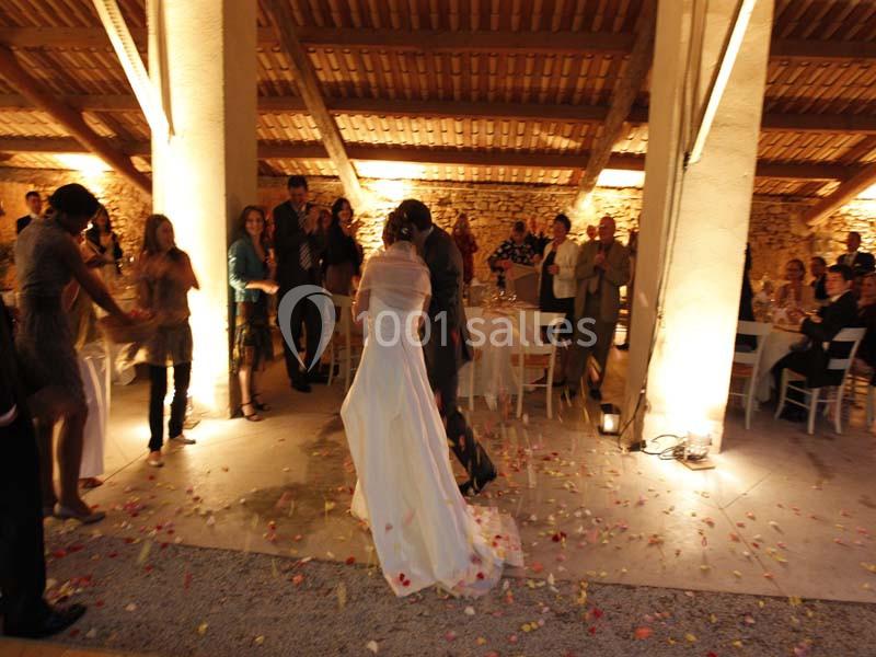 Location salle Piolenc (Vaucluse) - Château Beauchêne #11 Un couple danse au centre d'une salle éclairée, entouré d'invités et de pétales de fleurs au sol.