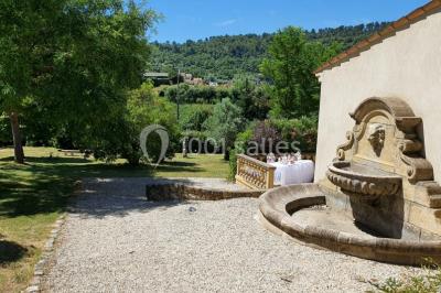Salle avec de grandes presses anciennes en bois et une longue table dressée pour un repas.