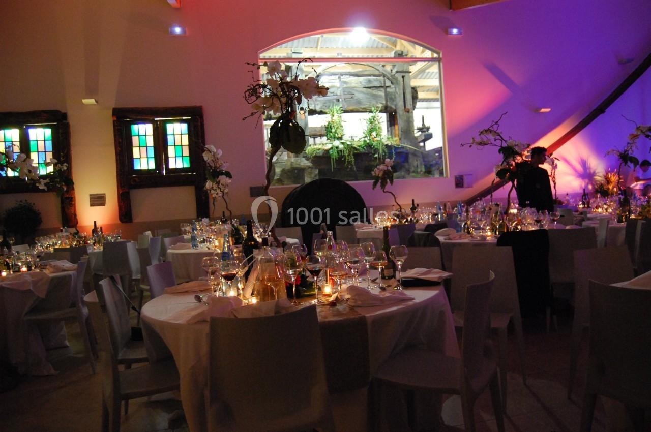 Salle de réception décorée avec des tables dressées, éclairage tamisé et ambiance chaleureuse.