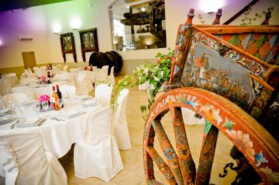 Salle avec de grandes presses anciennes en bois et une longue table dressée pour un repas.