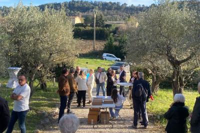 Salle avec de grandes presses anciennes en bois et une longue table dressée pour un repas.