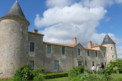 Miniature Location salle Sainte-Gemme-la-Plaine (Vendée) - Château de la Chevallerie #1 Un couple marche dans le jardin d'un château ancien entouré de verdure par une journée ensoleillée.