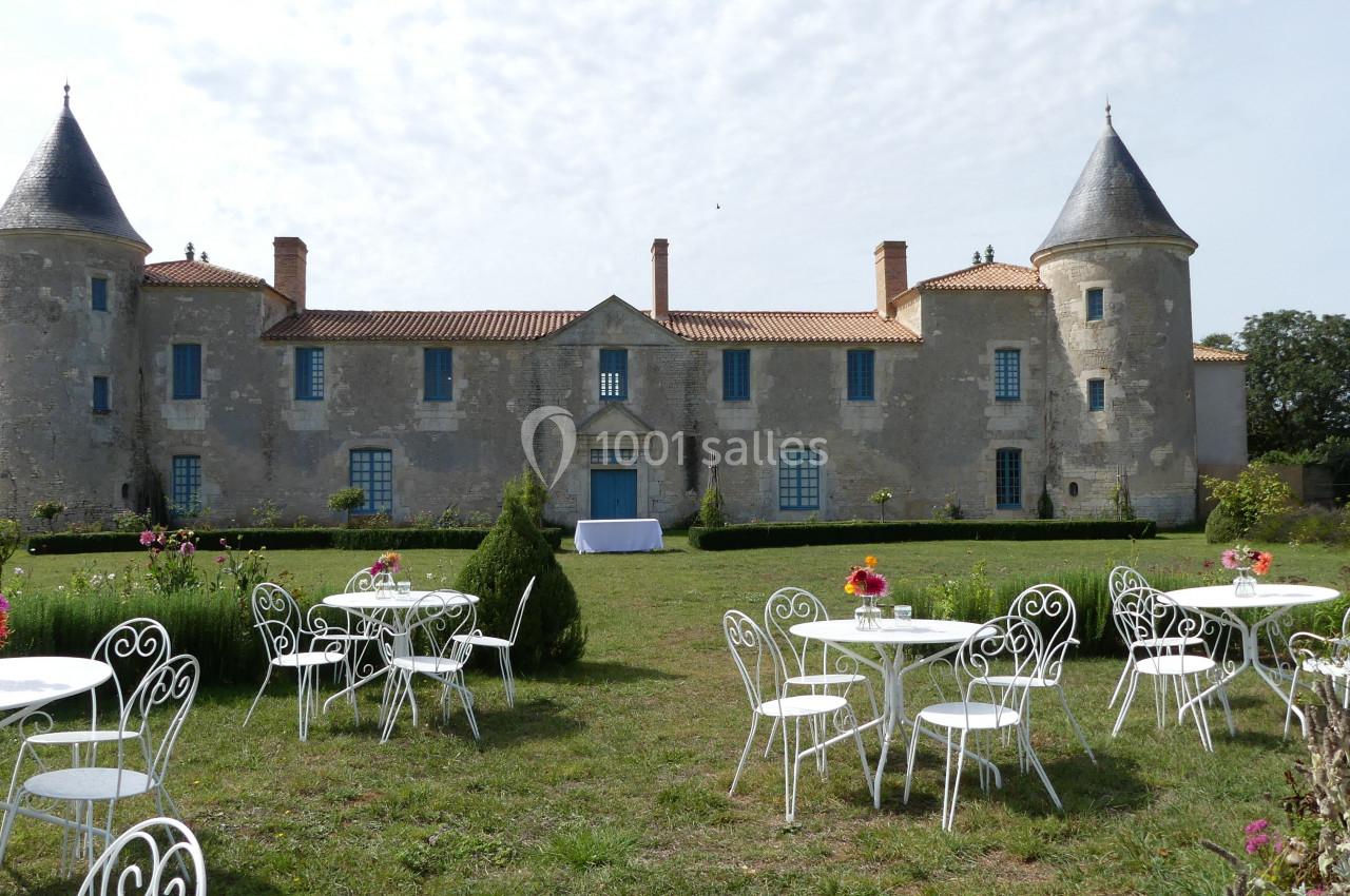 Location salle Sainte-Gemme-la-Plaine (Vendée) - Château de la Chevallerie #17 Façade d'un château ancien avec deux tours, entouré de tables blanches et d'un jardin fleuri.