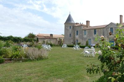 Miniature Location salle Sainte-Gemme-la-Plaine (Vendée) - Château de la Chevallerie #43 Un couple marche dans le jardin d'un château ancien entouré de verdure par une journée ensoleillée.