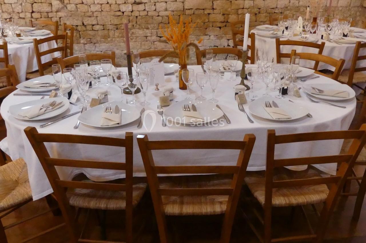 Location salle Sainte-Gemme-la-Plaine (Vendée) - Château de la Chevallerie #47 Table ronde dressée pour un repas, avec nappes blanches, vaisselle, verres et décoration florale au centre.