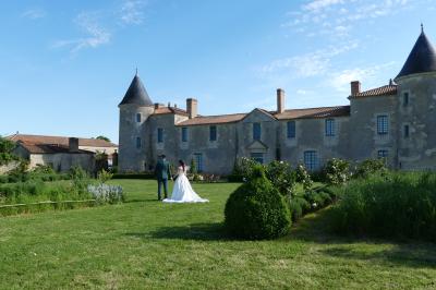 Miniature Location salle Sainte-Gemme-la-Plaine (Vendée) - Château de la Chevallerie #50 Un couple marche dans le jardin d'un château ancien entouré de verdure par une journée ensoleillée.