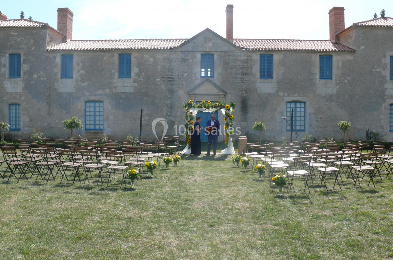 arche classique Chaises alignées en extérieur devant une arche fleurie, avec un bâtiment en pierre en arrière-plan.
