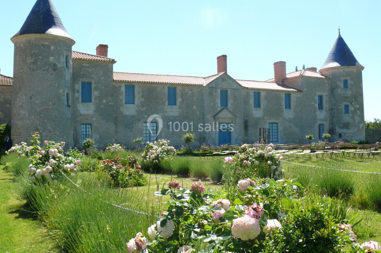 Cérémonie dans le jardin Façade d'un château en pierre avec tours, entouré d'un jardin fleuri et de pelouses bien entretenues.