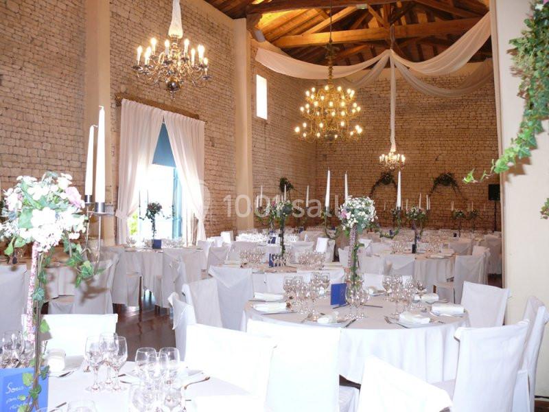 Grande Nef : 10 m de hauteur sous charpente Salle de réception décorée pour un mariage, avec tables dressées, chandeliers et drapés suspendus au plafond.